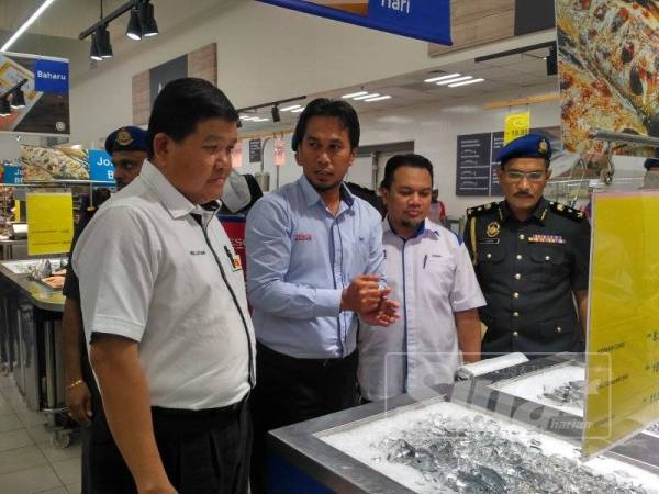 Loy Sian (kiri) meninjau harga barangan selepas pelancaran SHMMP di Tesco Extra Bukit Puchong hari ini