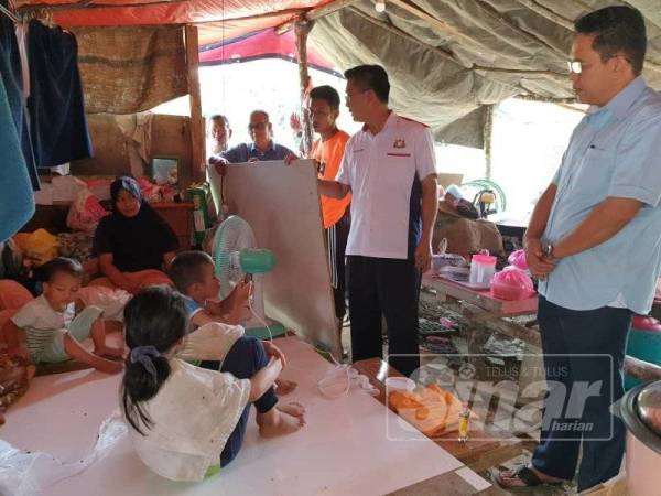 Dr Md Farid ( kanan) dan Tung Siong ( tengah) melihat keadaan Norhaslinda dan anak- anak tinggal di bangsal berbumbungkan kanvas, di Kampung Maju Jaya, Pekan Nanas semalam.

