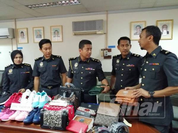 Azeem (tengah) bersama sebahagian barang tiruan yang dirampas dalam operasi di Bukit Bintang, semalam.