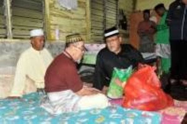 Aminolhuda (kanan) sewaktu menziarahi asnaf di DUN Parit Yaani di Masjid Felcra Sri Wangi, di sini, malam tadi.