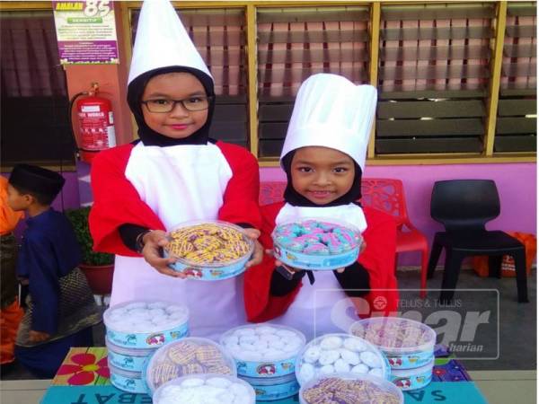Hannah (kiri) dan Hayrah menunjukkan tiga jenis biskut raya yang mereka hasilkan untuk diberikan rakan-rakan golongan yang asnaf. 