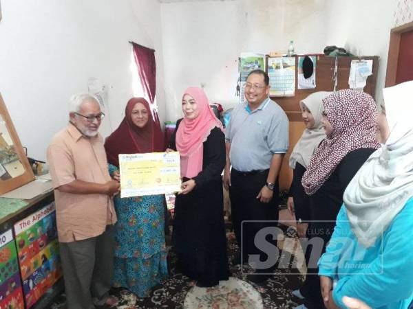 Halimaton Saadiah (tiga dari kiri) menyerahkan faedah pengurusan mayat kepada Haniza dan Ahmad Puad.