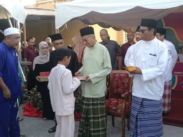 Dr Mahathir (tengah) menyerahkan sumbangan kepada kanak-kanak pada Majlis Berbuka Puasa dan Kebajikan bersama Perdana Menteri di Masjid Nurus Salam, Ewa, di sini tadi.