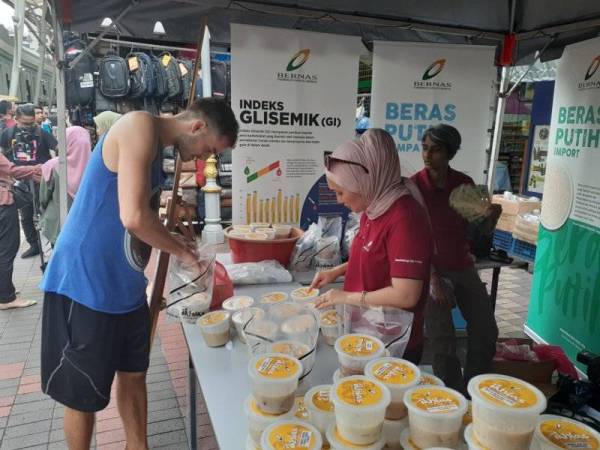 Pelancong tidak ketinggalan mendapatkan bubur lambuk antarabangsa yang diedarkan Bernas semalam.