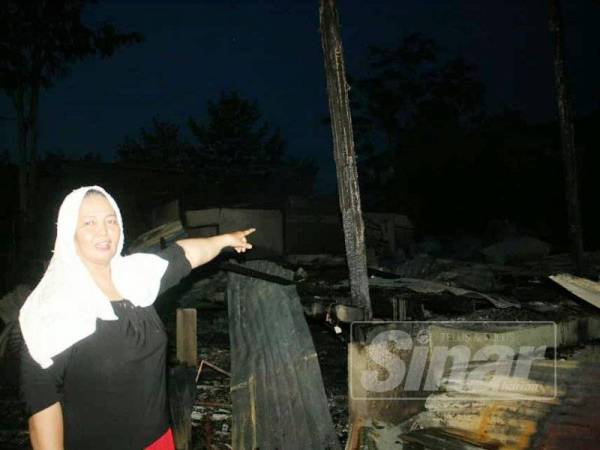 Noriah menunjukkan rumah jiran yang terletak di hadapan rumahnya musnah dalam kebakaran.