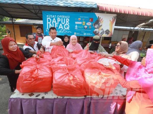 Badrul (tiga dari kiri) bersama sukarelawan menyusun bungkusan makanan untuk berbuka puasa yang akan diagihkan kepada asnaf di pusat operasi di Masjid Lama Bukit Sekilau.
