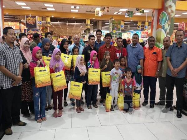 Asmuni (enam, kanan) bersama sebahagian anak-anak yatim yang menerima sumbangan baju raya sempena program berkenaan di Pasar raya Mydin Manjoi, di sini hari ini.