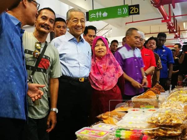 Dr Mahathir (tiga dari kiri) bertanyakan jenis kuih yang dijual kepada Suria ketika mengunjungi gerai Warisan Mak Chah.