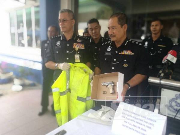 Hasanuddin (kiri) menunjukkan rampasan pistol dan jaket PDRM di Rantau Panjang.