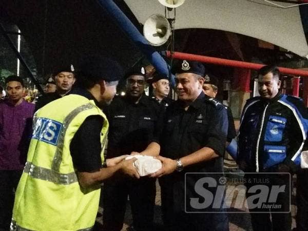 Aidi (tengah) menyerahkan juadah sahur kepada salah seorang anggota polis yang bertugas.