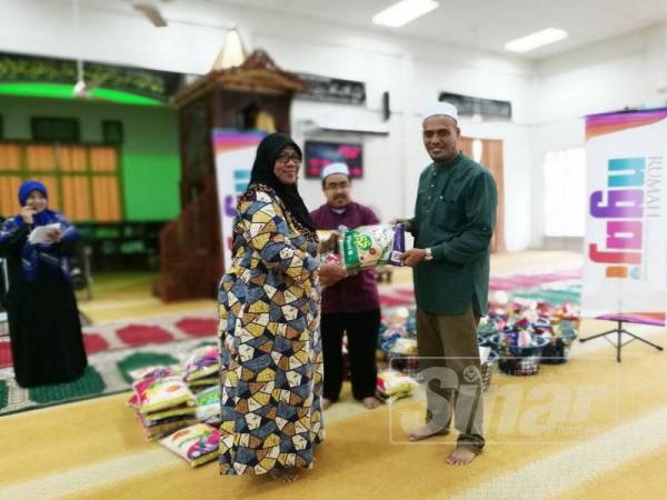 Pengerusi Majlis Pengurusan Komuniti Kampung (MPKK) PPR Hiliran, Zabri Awang (kanan) menyampaikan sumbangan kepada asnaf.