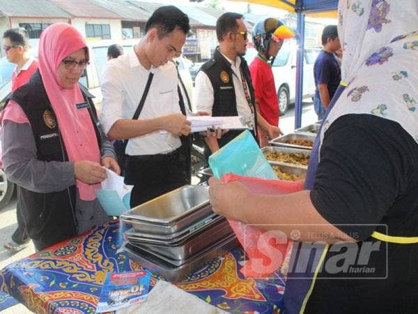 Surinah (kiri) melakukan pemeriksaan ketika operasi di bazar Ramadan Ayer Baloi kelmarin.