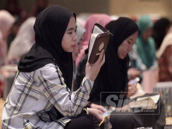 Seorang kakitangan TH khusyuk membaca al-Quran pada Majlis Khatam al-Quran dan Majlis Penutupan Program RSR di Dewan Besar TH.