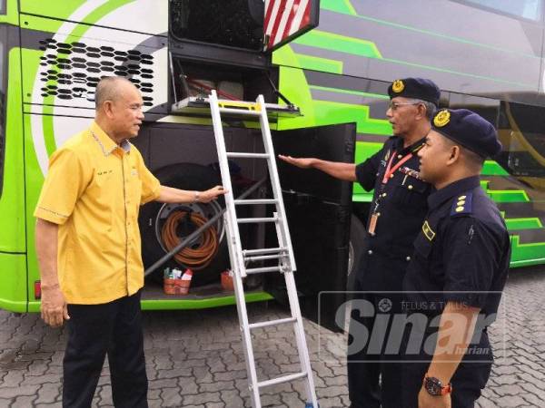 Che Ibrahim (kiri) memberi penerangan kepada Mahasan (tengah) ketika memeriksa pintu dan tangga kecemasan pada bas ekspres Mutiara hari ini.