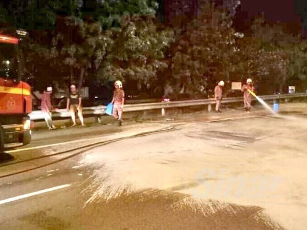 Anggota Balai Bomba dan Penyelamat Wakaf Tapai membersihkan tumpahan minyak di lokasi kejadian.