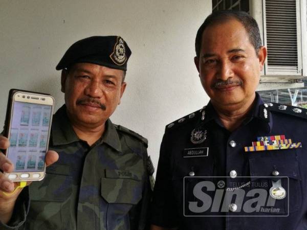 Abdullah (kanan) dan Ramly menunjukkan wang tunai berjumlah RM10,000 yang ditawarkan oleh dua lelaki kepada anggotanya.