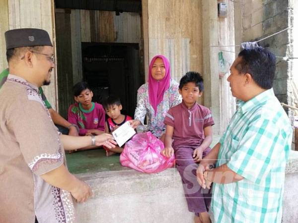 Mohd Rusli (kiri) bersama Dr Zulkepli menyampaikan sumbangan wang tunai dan barang keperluan dapur ketika menziarahi Samsiah Alni di rumahnya di Kampung Cherang Melintang, Tumpat. 