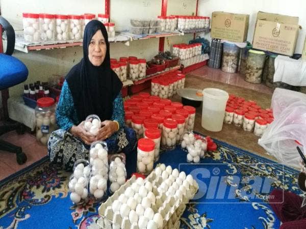 Rohani menyusun bekas yang mengandungi telur itik yang sedang direndam air garam untuk dijadikan telur masin.