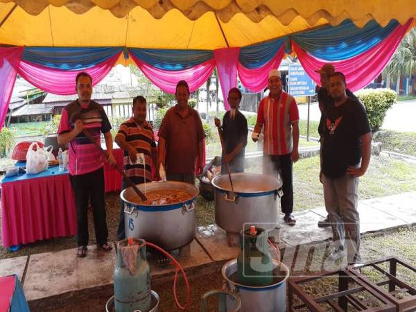 Tok Lan (tengah) mengacau bubur lambuk dalam satu aktiviti komuniti di Felda Taib Andak
