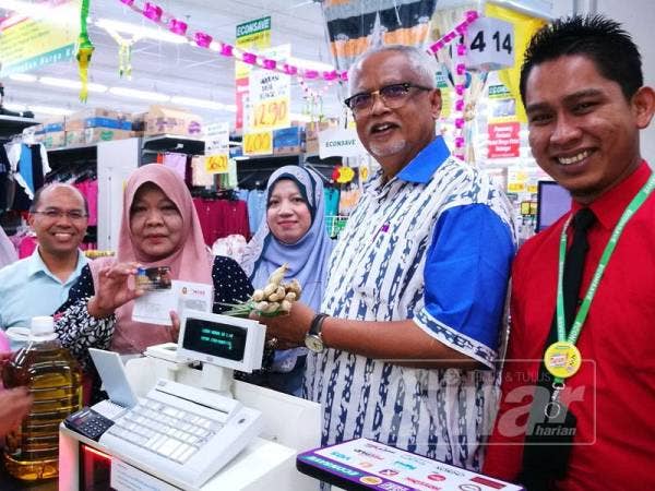 Mahfuz (dua, kanan) meninjau penggunaan kad KIDA oleh penerima, Zaleha Zakaria (empat, kanan) ketika membeli-belah di Pasaraya Econsave Pokok Sena.