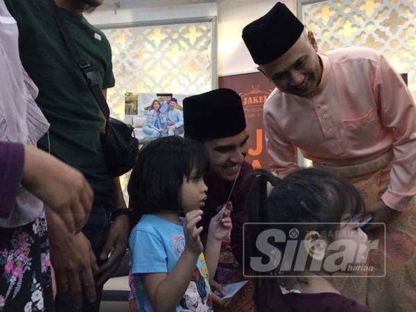 Mohd Fuad (kanan) menyampaikan sumbangan kepada 50 asnaf fakir miskin yang terdiri daripada orang kelainan upaya (OKU) dan miskin bandar di Jakel Mall hari ini.