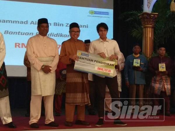 Syed Mohd Ghazali Wafa menyampaikan sumbangan kepada Muhammad Aiman yang menerima bantuan pendidikan.