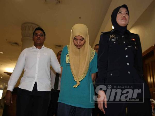 Siti Noor Faezah (tengah) dibawa keluar dari kompleks Mahkamah Majistret di sini.