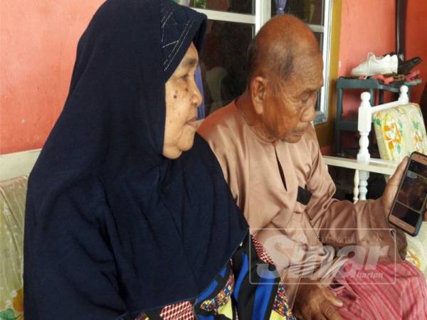 Abd Razak bersama isterinya Jemah Jamaludin, 76, menunjukkan gambar kenangan Norhamidah bersama suami dan anak-anaknya ketika Syawal tahun lalu.
