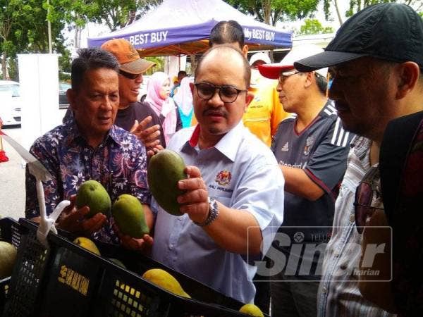 Samudin (kiri) mengiringi Shamsul Iskandar melihat buah mangga harum manis yang turut dijual pada program My Best Buy Pra Aidilfitri di Taman Tasek Ayer Keroh, di sini hari ini.