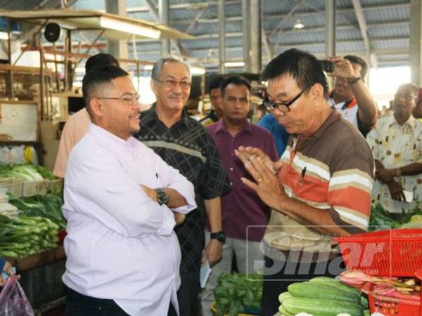 Mujahid (kiri) tekun mendengar permasalahan dikemukakan peniaga sayur sewaktu melawat Pasar Awam Parit Buntar hari ini.