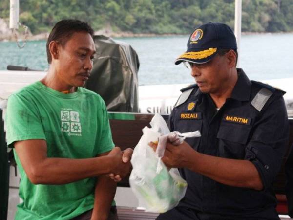 Rozali (kanan) menyerahkan sumbangan juadah berbuka puasa kepada nelayan yang ditemui. - Foto APMM Kedah/Perlis