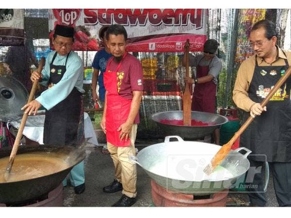 Asmuni (kiri) bersama Idris (kanan) turut membantu mengacau dodol yang dimasak dan dijual kepada pelanggan di gerai My Best Buy RTC Perak.