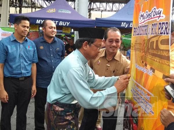 Asmuni menurunkan tandatangan di gegantung program sebagai gimik perasmian sambil disaksikan Idris (kanan) di RTC Perak, di sini semalam.