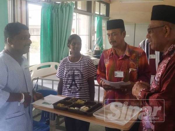Md Nayan (kanan) menyantuni seorang pesakit di wad lelaki Hospital Parit Buntar sewaktu majlis penyampaian sumbangan Aidilfitri kepada pesakit hospital itu, hari ini.