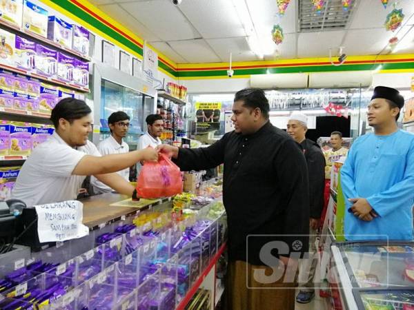 Muhamad Arafat menyampaikan pek makanan sahur kepada pekerja kedai serbaneka.