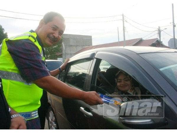 Abdullah menyerahkan risalah kempen kepada pengguna jalan raya semasa kempen Op Selamat peringkat IPD Pasir Mas di Markas Aksem di Cabang Empat Salam, Rantau Panjang.