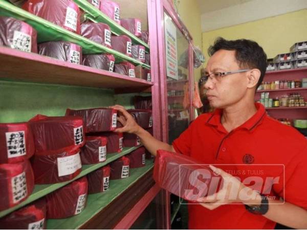 Mohd Nasrun menyusun songkok di kedainya mengikut saiz.