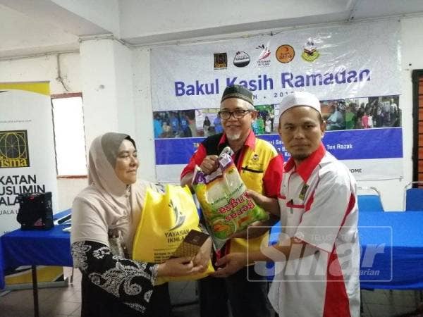 Osman (kanan) menyampaikan duit raya dan pek makanan kepada salah seorang penerima dalam program Bakul Kasih Ramadan di PPR Desa Tun Razak, Sabtu lalu.