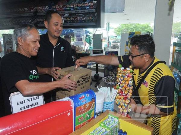 Pengunjung stesen minyak Petronas menderma untuk Tabung Misi Wakaf Al-Quran Setulus Ikhlas di Stesen Minyak Petronas Jalan Reko Kajang di sini hari ini. - FOTO ROSLI TALIB