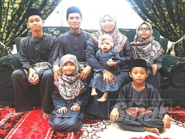 Siti Zubaidah memangku Aaira pada pagi Syawal di rumah mereka di Kampung Sungai Kuali.