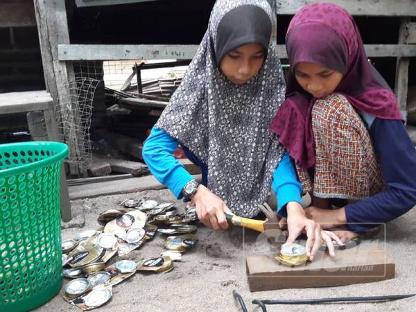 Siti Nur Zulaikha (kiri) dan adiknya, Siti Nurul Huda Insyirah mengetuk tin minuman yang dicari untuk dijual. 