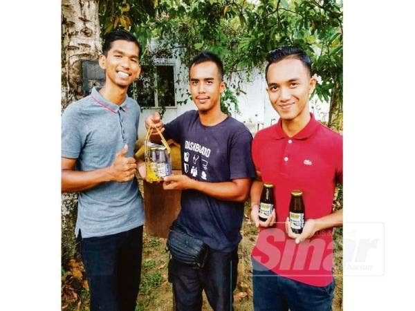 Mohd Amirul (tengah) melayan pelanggan membeli madu lebah kelulut yang dibotolkan.