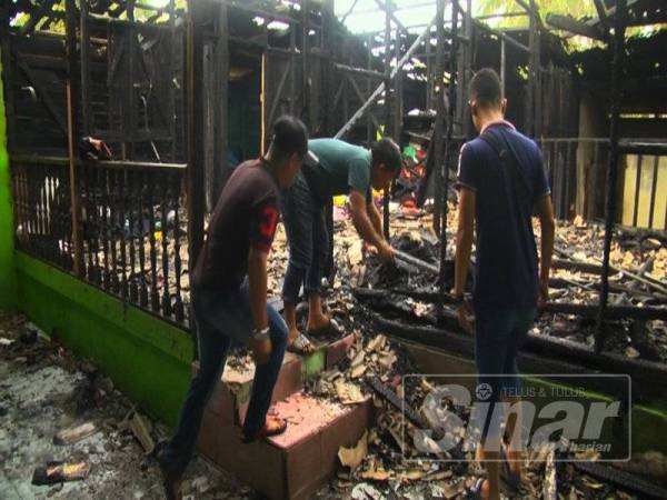 Ahli keluarga Mohd Rafiq menyelongkar sisa kebakaran selepas kebakaran berjaya dipadamkan.
