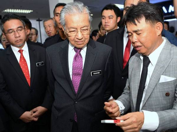 Tun Dr Mahathir (dua, kiri) mendengar penerangan yang disampaikan oleh Pengarah Urusan Triplus Industry Sdn. Bhd. Yeon Kok Kuang (kanan) ketika melawat gerai pameran selepas merasmikan Smart Industry Centre, Konica Minolta Business Technologies Malaysia Sdn Bhd, pada lawatan sehari ke Melaka hari ini. - Foto Bernama
