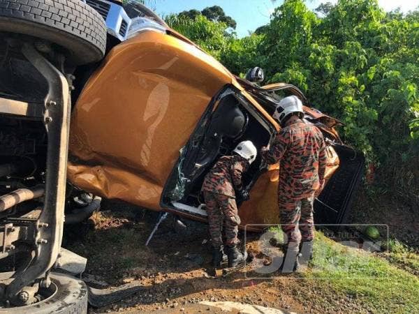 Dua anggota bomba melihat Nissan Navara dinaiki lima sekeluarga yang dirempuh sebuah lori pasir di persimpangan lampu isyarat Jalan Masjid Tanah-Kampung Jeram petang semalam.