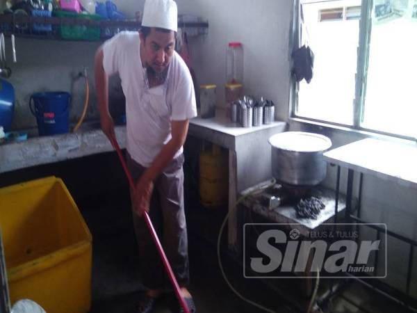 Wahid terpaksa membersihkan kedai makan miliknya yang turut terjejas akibat banjir kilat.