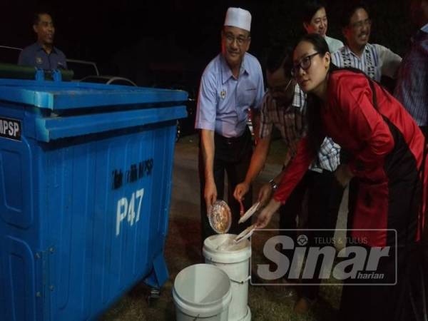 Rozali (tengah) membuang sampah mengikut tong khas yang disediakan untuk pengasingan sisa di punca yang disediakan pada Majlis Rumah Terbuka Aidilfitri KADUN Jawi.