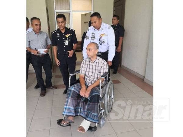 Anggota trafik membantu tertuduh yang berkerusi roda.