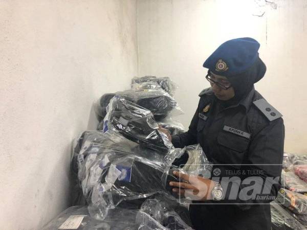 Pegawai KPDNHEP memeriksa selipar tiruan yang disita dalam pemeriksaan sebuah premis di Kawasan Perindustrian Menglembu, semalam. 