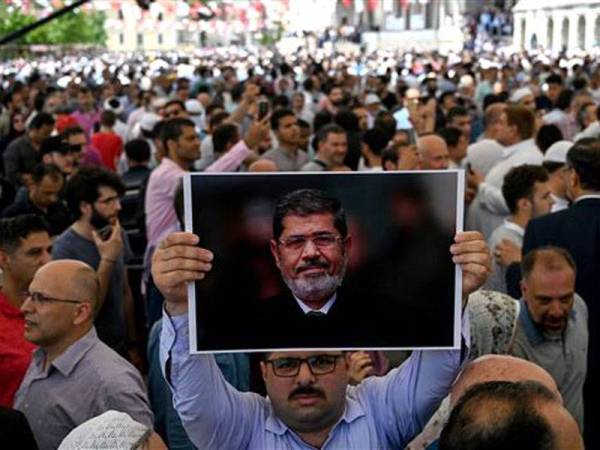 Seorang lelaki memegang potret Mursi ketika pengebumian simbolik pemimpin itu di Masjid Fatih di Istanbul kelmarin.